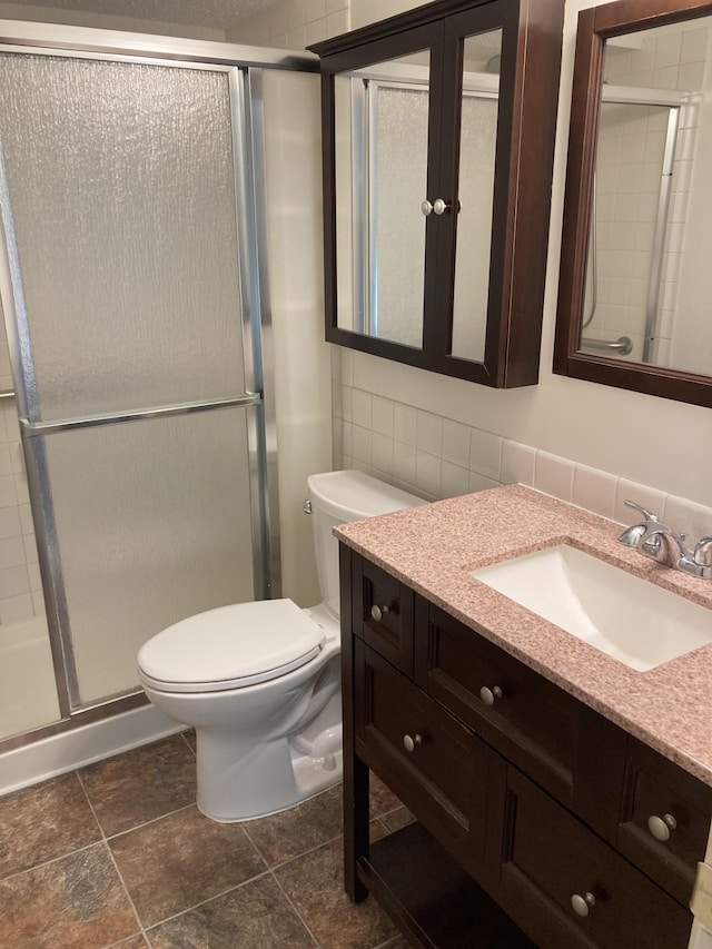bathroom with toilet, a stall shower, vanity, and decorative backsplash