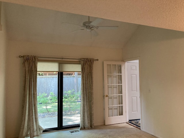 empty room featuring healthy amount of natural light, ceiling fan, carpet, lofted ceiling, and baseboards