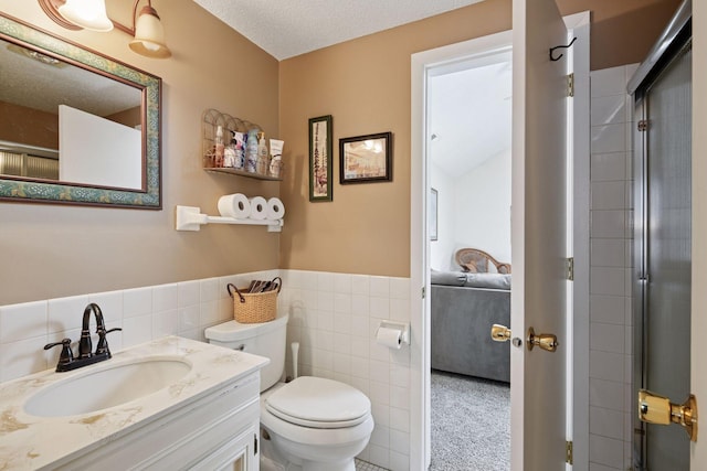 bathroom with tile walls, connected bathroom, toilet, wainscoting, and vanity