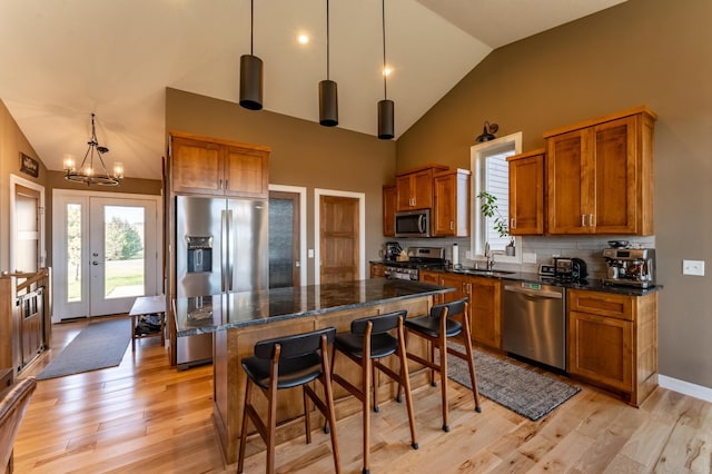 21107 Ghia St NE, East Bethel, MN 55011 - kitchen featuring a notable chandelier, light wood-style floors, brown cabinets, a breakfast bar area, and appliances with stainless steel finishes