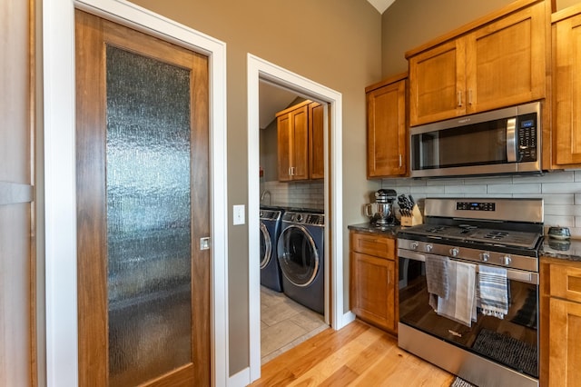 21107 Ghia St NE, East Bethel, MN 55011 - kitchen featuring separate washer and dryer, appliances with stainless steel finishes, light wood-style floors, brown cabinetry, and backsplash