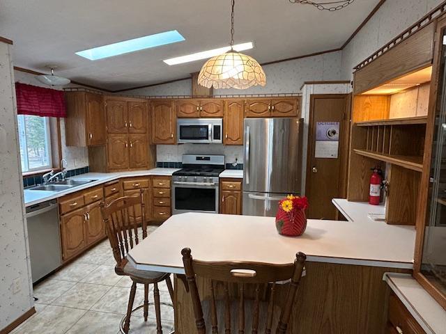 54966 Rainbow Rd, Sand Lake Twp, MN 56636 - kitchen featuring stainless steel appliances, vaulted ceiling, a skylight, brown cabinetry, and light countertops