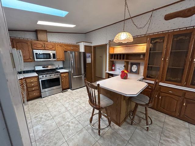 54966 Rainbow Rd, Sand Lake Twp, MN 56636 - kitchen featuring stainless steel appliances, light countertops, a kitchen breakfast bar, brown cabinetry, and a peninsula