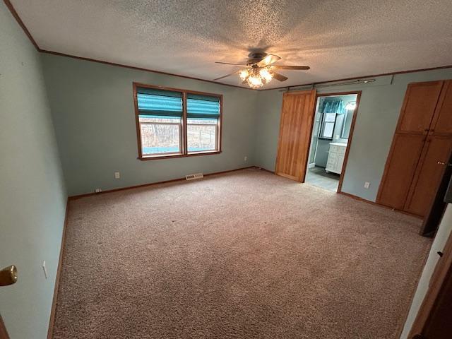 54966 Rainbow Rd, Sand Lake Twp, MN 56636 - unfurnished bedroom with a textured ceiling, light carpet, ensuite bathroom, ceiling fan, and crown molding