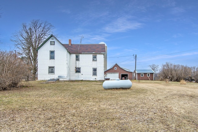 back of property featuring an outdoor structure, a lawn, and a chimney