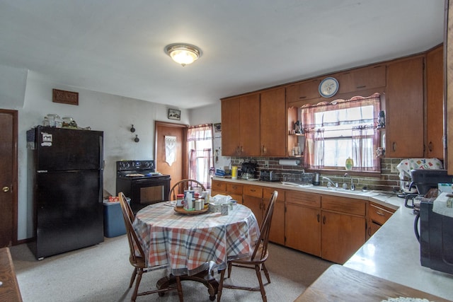 kitchen with a sink, light countertops, black appliances, and a healthy amount of sunlight