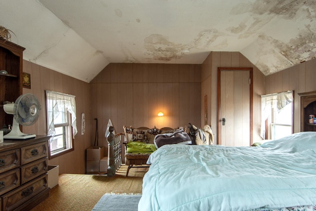 carpeted bedroom featuring wooden walls and vaulted ceiling