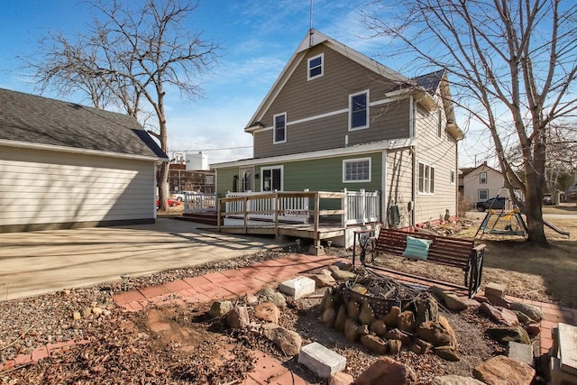 back of house with a wooden deck, a fire pit, and a patio area