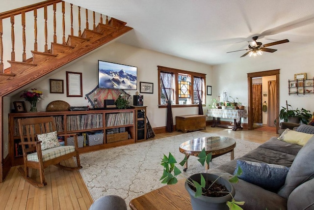 living area featuring stairway, hardwood / wood-style flooring, and a ceiling fan