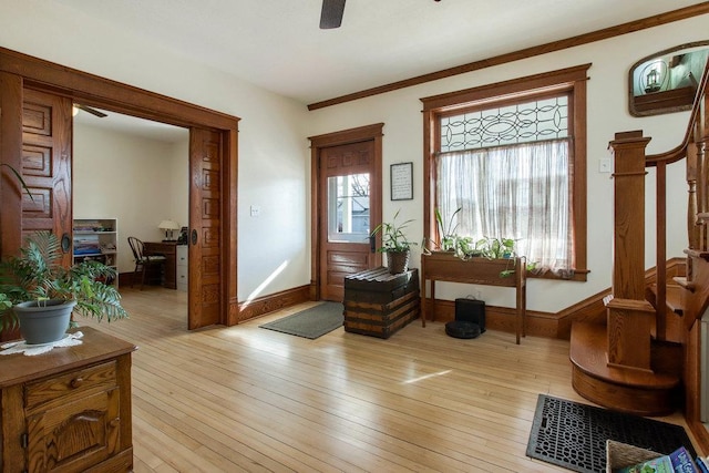 interior space with ornamental molding, ceiling fan, light wood-style flooring, and stairs