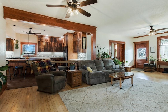 living room featuring hardwood / wood-style flooring, ceiling fan, and beamed ceiling