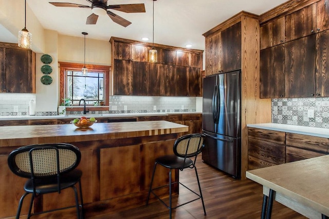 kitchen featuring tasteful backsplash, a sink, ceiling fan, wooden counters, and freestanding refrigerator