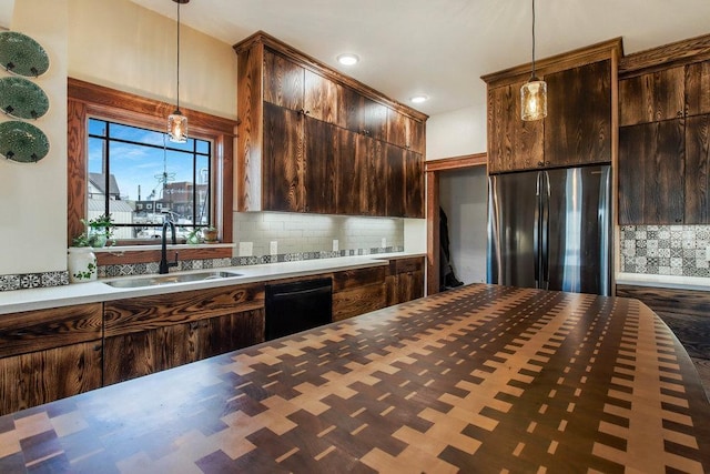 kitchen with dishwasher, a sink, dark brown cabinets, and stainless steel refrigerator