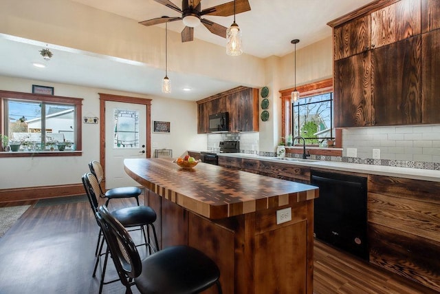 kitchen featuring decorative backsplash, a sink, black appliances, butcher block countertops, and dark wood finished floors