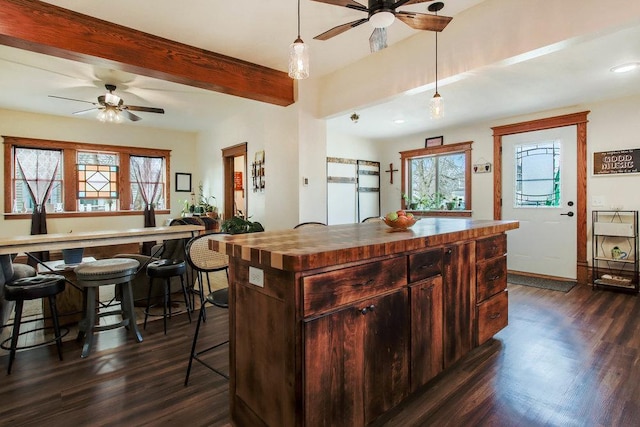 kitchen featuring dark wood-type flooring, a ceiling fan, and beamed ceiling