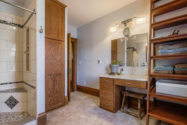 bathroom featuring baseboards, a tile shower, tile patterned flooring, and vanity