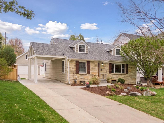 cape cod home with stone siding, a shingled roof, a front lawn, driveway, and an outdoor structure