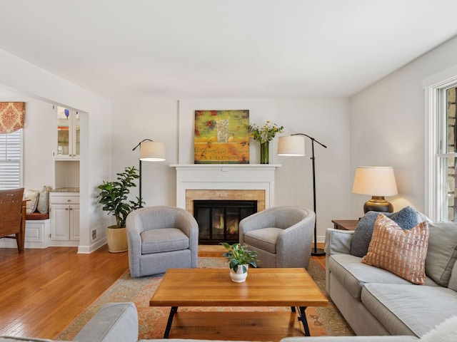living room with light wood finished floors, a glass covered fireplace, and baseboards