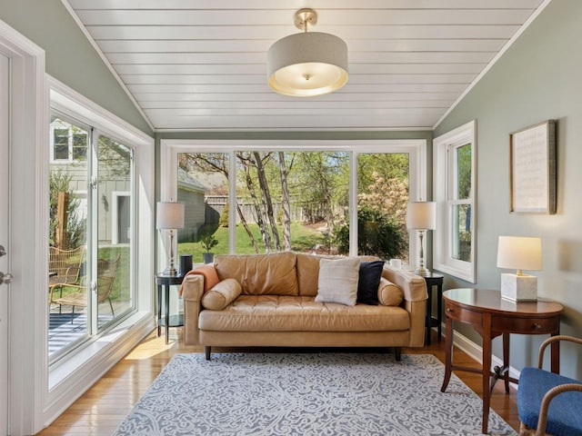 sunroom / solarium featuring vaulted ceiling, plenty of natural light, wood finished floors, wooden ceiling, and crown molding
