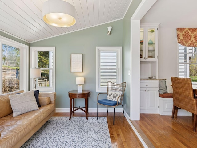 living room featuring ornamental molding, vaulted ceiling, light wood-style floors, wood ceiling, and baseboards