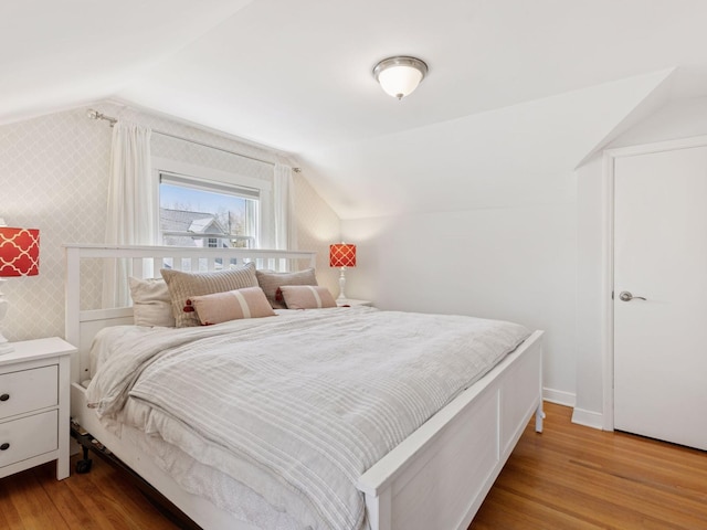 bedroom featuring lofted ceiling, wood finished floors, and baseboards