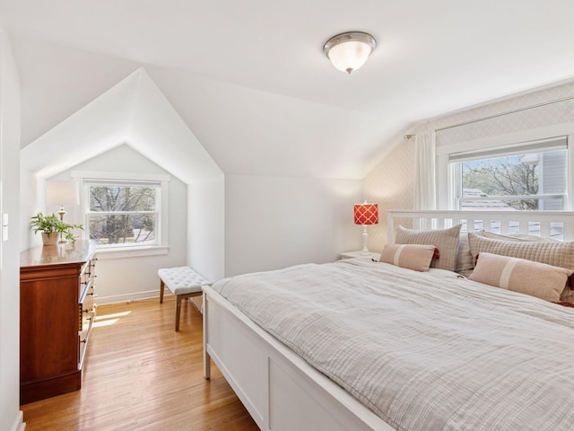bedroom with vaulted ceiling, light wood finished floors, and baseboards