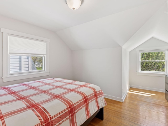 bedroom featuring lofted ceiling, light wood finished floors, and baseboards