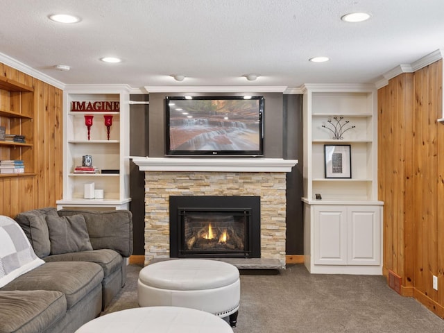 living room with carpet floors, a textured ceiling, built in shelves, crown molding, and a fireplace