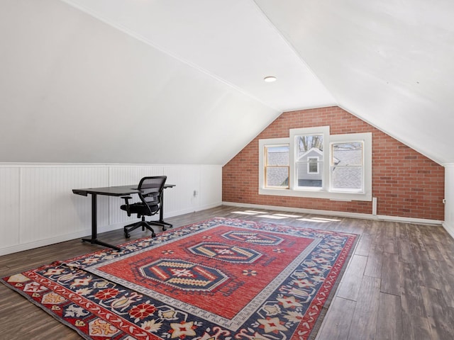 office area with wood finished floors, lofted ceiling, and brick wall