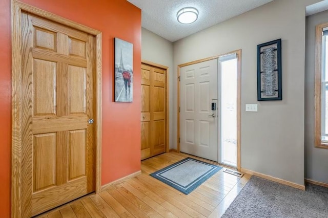 11373 Balsam Way, Woodbury, MN 55129 - entryway featuring visible vents, baseboards, a textured ceiling, and wood finished floors