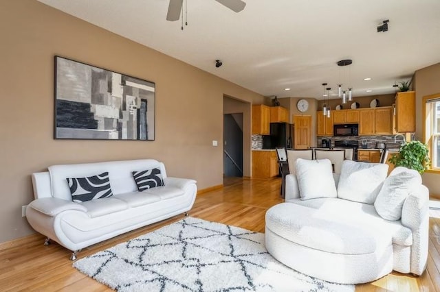 11373 Balsam Way, Woodbury, MN 55129 - living area featuring light wood-style flooring, ceiling fan, and baseboards