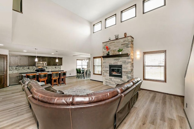 1408 72nd Ave S, Fargo, ND 58104 - living room with a high ceiling, a stone fireplace, baseboards, and light wood-type flooring