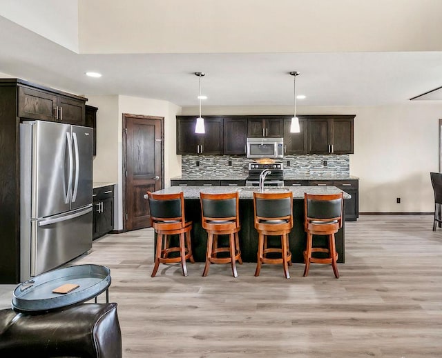 1408 72nd Ave S, Fargo, ND 58104 - kitchen with stainless steel appliances, light wood finished floors, decorative backsplash, a center island with sink, and recessed lighting