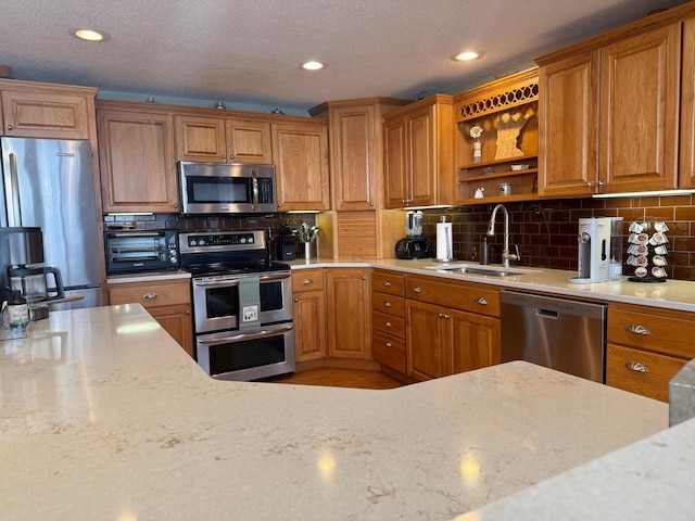 kitchen with appliances with stainless steel finishes, brown cabinetry, and a sink