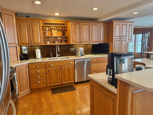 kitchen with a sink, appliances with stainless steel finishes, tasteful backsplash, and light countertops