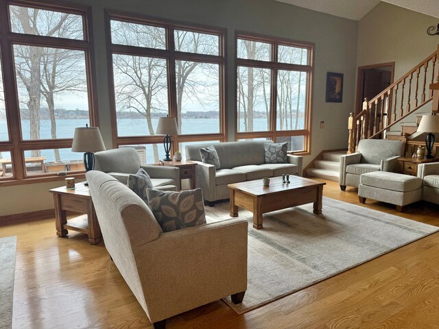 living area with a water view, plenty of natural light, stairway, and light wood-style floors
