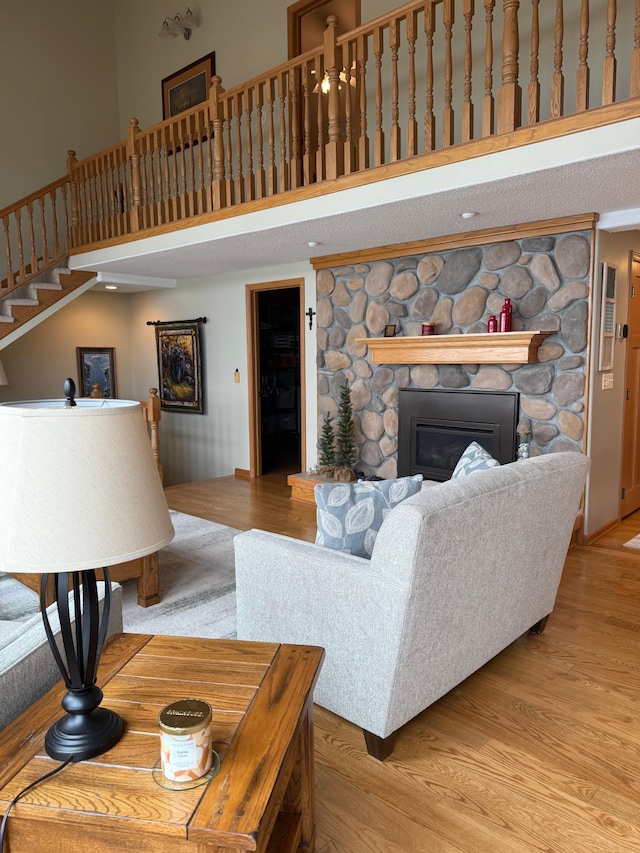 living area with wood finished floors, stairs, a high ceiling, and a fireplace