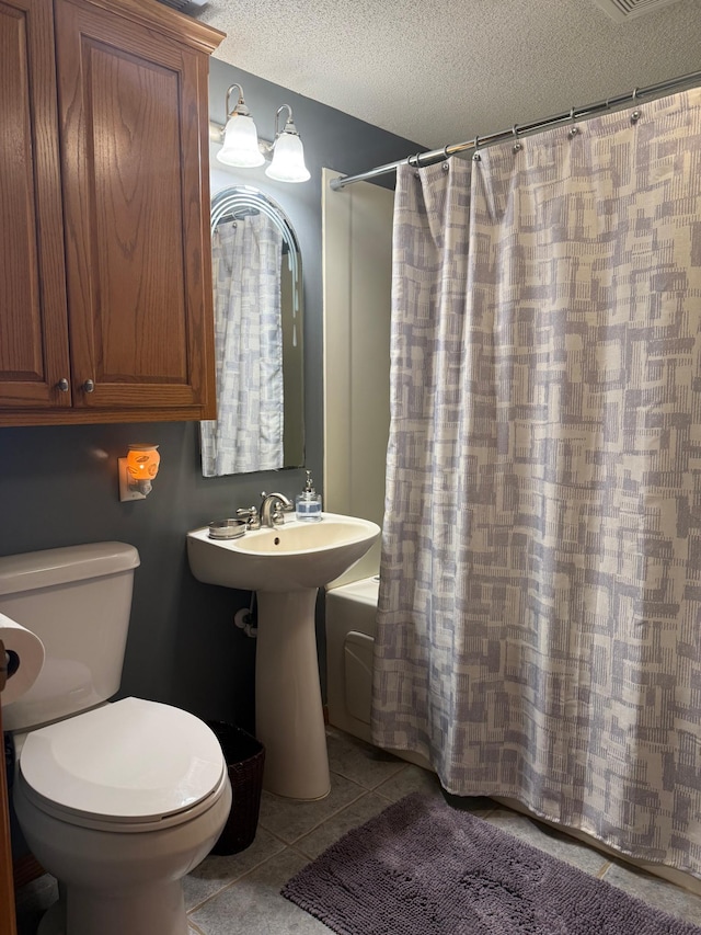 bathroom with tile patterned flooring, toilet, and a textured ceiling