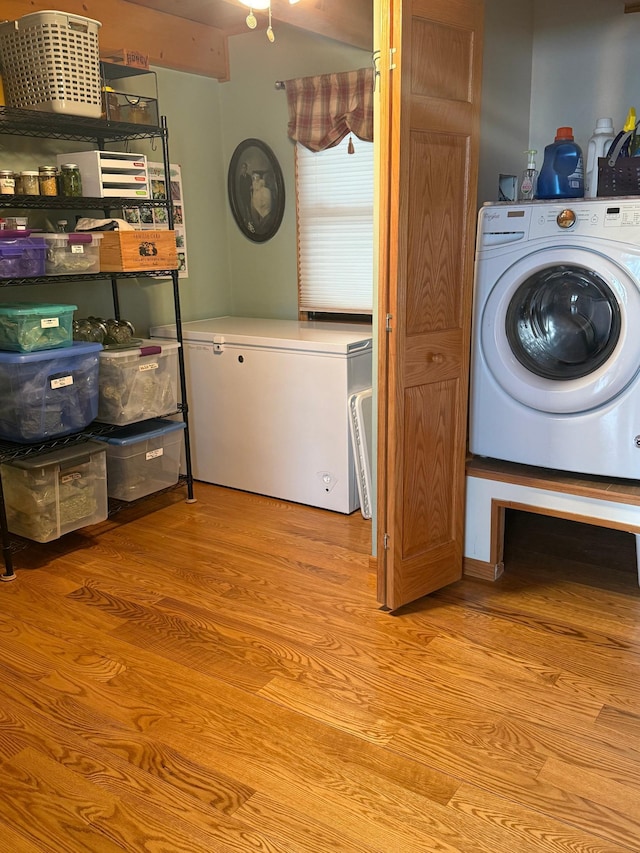 clothes washing area featuring light wood-style flooring and washer / clothes dryer