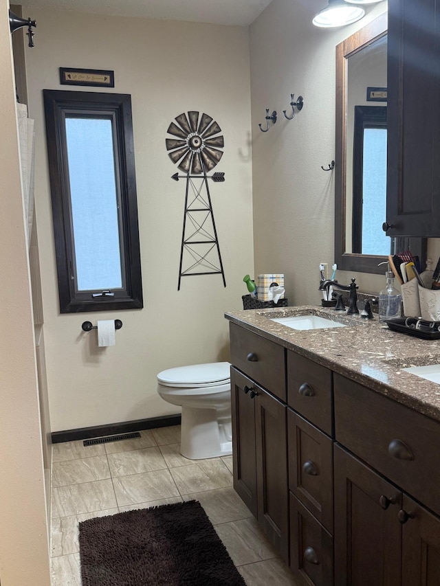 bathroom with vanity, baseboards, toilet, and visible vents