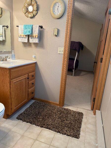 bathroom featuring toilet, baseboards, tile patterned flooring, and vanity