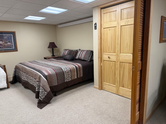 carpeted bedroom with baseboards and a drop ceiling