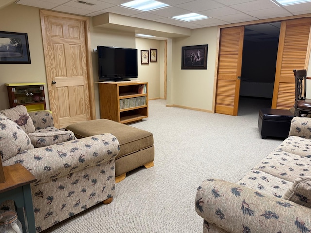 carpeted living area with baseboards, a drop ceiling, and visible vents