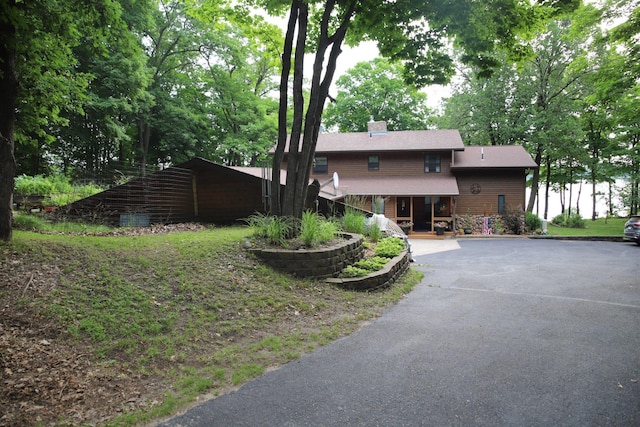 view of front facade featuring covered porch and a chimney
