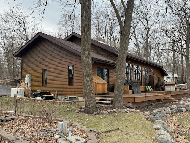 view of side of property featuring roof with shingles and a deck