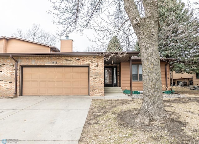 1611 32nd St S, Fargo, ND 58103 - view of front of home with a garage, brick siding, driveway, and a chimney