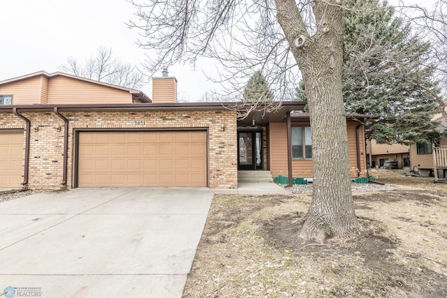 1611 32nd St S, Fargo, ND 58103 - ranch-style house featuring a chimney, a garage, concrete driveway, and brick siding