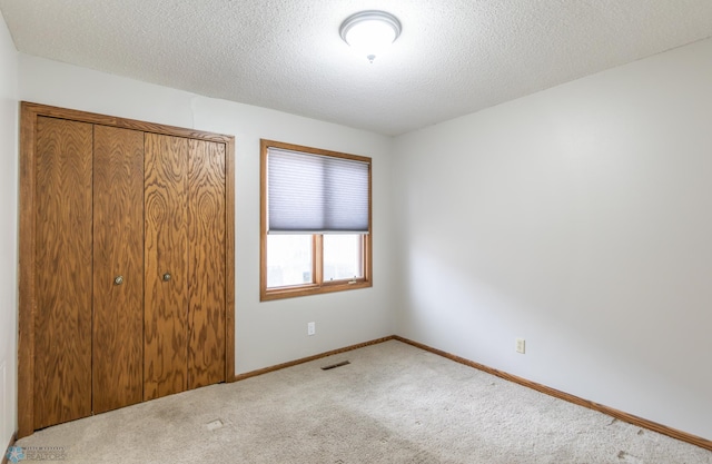 1611 32nd St S, Fargo, ND 58103 - unfurnished bedroom featuring a closet, baseboards, visible vents, a textured ceiling, and carpet floors