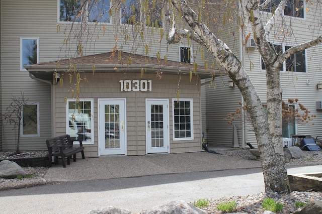 view of exterior entry featuring a patio and a shingled roof