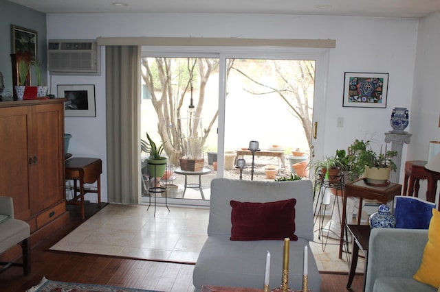 living area with a wall unit AC and wood finished floors